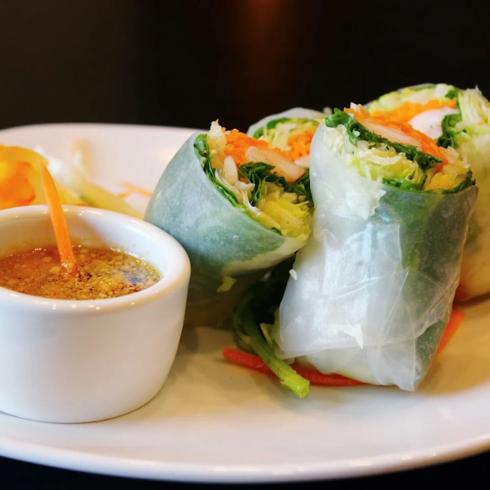 Fresh Goji Y Agave spring rolls filled with vegetables and shrimp, served with a dipping sauce.